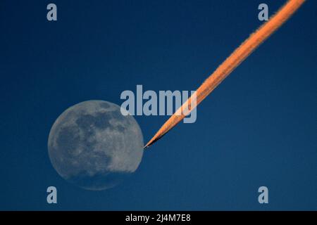 Prague, République tchèque. 16th avril 2022. Un avion laisse un sentier de condensation au coucher du soleil et survole la « Supermoon » au-dessus de la République tchèque, près de Prague. Une superlune se produit lorsque la lune est particulièrement proche de la Terre lorsqu'elle est pleine. Cette pleine lune d'avril s'appelle la Supermoon rose. (Credit image: © Slavek Ruta/ZUMA Press Wire) Credit: ZUMA Press, Inc./Alamy Live News Banque D'Images