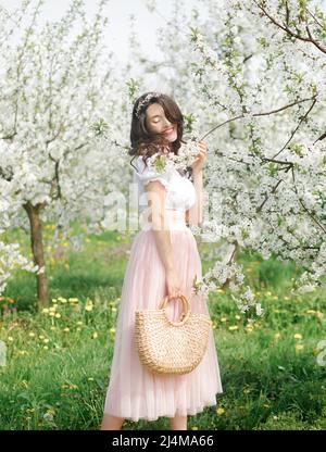 Portrait de printemps d'une belle fille dans une robe étonnante appréciant le printemps dans un jardin frais en fleurs Banque D'Images