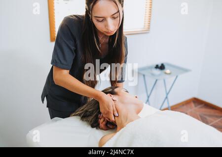 Femme thérapeute effectuant un massage du cou à une patiente inclinée de la tête. Détente et détente Banque D'Images