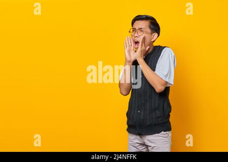 Portrait d'un jeune asiatique hurlant avec une expression choquée sur fond jaune Banque D'Images