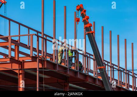 Les constructeurs fixent des poutres en fer avec une grue. Structure du châssis. Banque D'Images