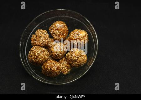 Les boules de sésame sont dans une tasse. Sur fond noir Banque D'Images