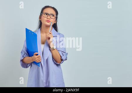 Portrait de la jeune femme asiatique concentré écrire des notes de planification créant la stratégie sur fond violet Banque D'Images