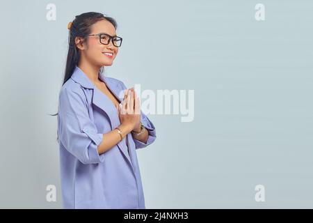 Portrait de la jolie jeune femme asiatique donne les mains de salutation avec un grand sourire isolé sur fond blanc Banque D'Images