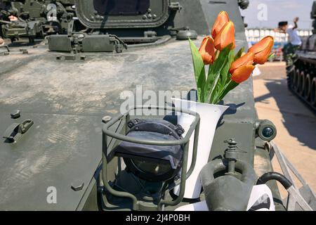 Des tulipes rouges dans un vase se tiennent sur un véhicule blindé de combat d'infanterie Banque D'Images