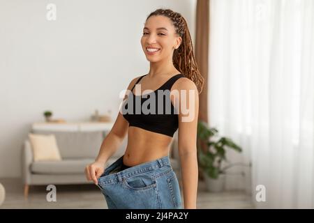 Happy Slim Black Lady porte un Jean extra-large à la maison Banque D'Images