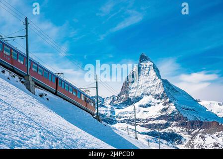 Train traversant le mont Cervin enneigé contre le ciel bleu Banque D'Images