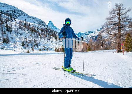 Skieur mâle skier sur un paysage couvert de neige contre la chaîne de montagnes de Matterhorn Banque D'Images