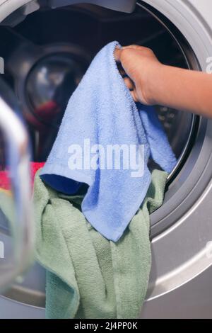 mettre une serviette et des chiffons dans un lave-linge. Banque D'Images