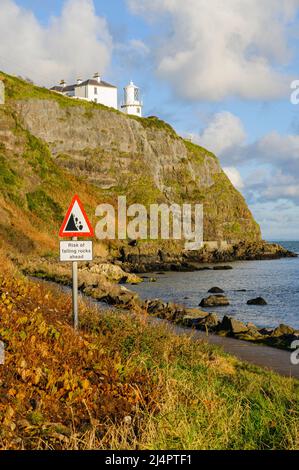 Panneau avertissant les marcheurs d'être conscients de la chute de rochers sur un chemin côtier le long du fond de certaines falaises. Banque D'Images