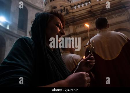 Un adorateur chrétien tient une bougie et une branche d'olivier pendant qu'elle participe à un service religieux pendant la célébration du samedi Saint dans la partie sud-est de l'Église du Saint-Sépulcre dans la vieille ville de Jérusalem Israël Banque D'Images