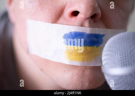 Passer la bande sur sa bouche avec le drapeau de l'Ukraine, en essayant de parler dans un microphone. Le concept de liberté de la presse en Ukraine. Banque D'Images