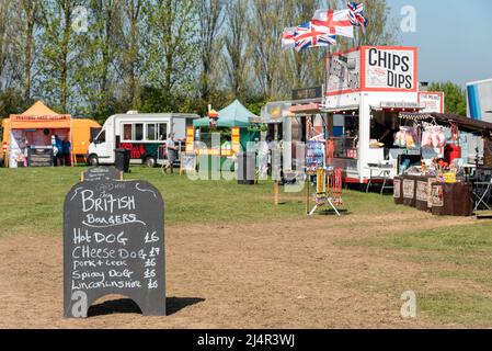 Les fournisseurs de produits alimentaires lors d'un événement à l'extérieur sont prêts pour les clients. Prix sur tableau noir pour les hamburgers britanniques, hot dog, cheese dog, porc, chien épicé, saucisses Banque D'Images