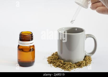 bouteille compte-gouttes d'huile de marijuana dans les mains de l'homme avec gobelet à perfusion, marijuana écrasée, fond blanc Banque D'Images