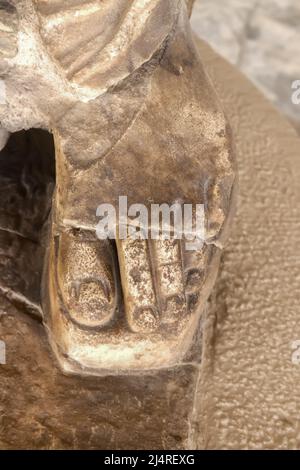 Gros plan du pied dans le sable avec les orteils montrant l'ancienne statue grecque - marbre granuleux sculpté sur un arrière-plan plus flou Banque D'Images