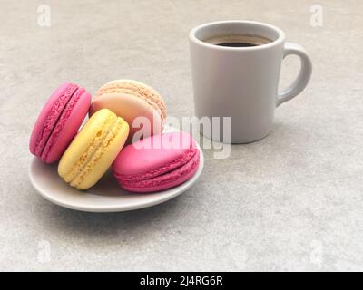 macarons, macarons colorés délicieux et magnifiques et une tasse de café sur une table ou un fond gris ou une surface avec espace de copie. café et biscuits conc Banque D'Images