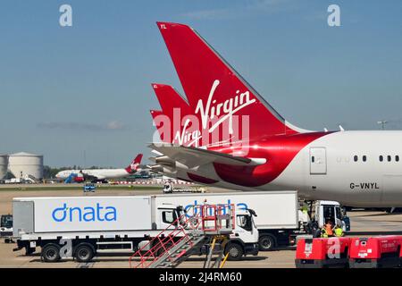 Londres, Angleterre - avril 2022 : ailettes de queue des Boeing de Virgin Atlantic Airways dans le terminal. Au premier plan se trouvent les camions de fret aérien Banque D'Images