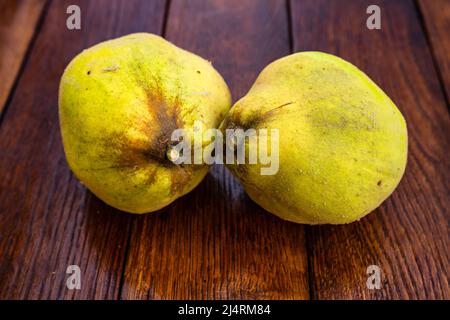 Coings isolés. Deux coings jaune sur une planche de bois. Banque D'Images