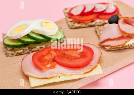 Différents pains à croûtes au jambon, à la tomate, au radis, au concombre et au fromage. Petit déjeuner facile. Alimentation. Sandwichs rapides et sains. Croustillant et garniture savoureuse. En-cas diététiques Banque D'Images