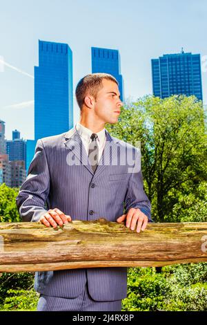 Un jeune homme d'affaires attend à l'extérieur. Portant officiellement un costume bleu, une cravate noire, un jeune homme professionnel est debout devant le quartier des affaires Banque D'Images