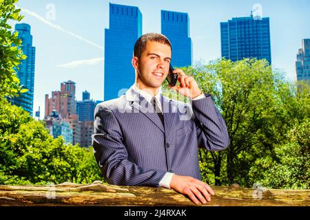 Jeune homme d'affaires au téléphone. Dressing formellement dans un costume bleu, cravate noire, un jeune étudiant d'université est debout devant le quartier des affaires, ma Banque D'Images