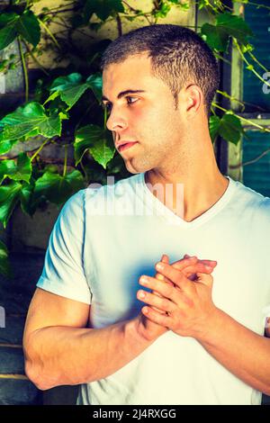 Portrait du jeune homme, portant un T-shirt blanc à col en V, cheveux courts, saisir les mains Banque D'Images