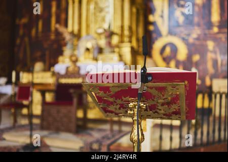 détail d'un lutrin doré avec livre et microphone sur l'autel d'une église Banque D'Images