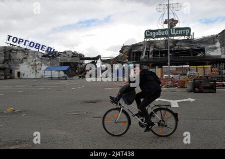 Un homme avec un enfant fait une balade en vélo devant un centre commercial détruit qui a été endommagé par les bombardements de l'armée russe dans la ville de Bucha. À Borodyanka, dans la région de Kiev, les sauveteurs ont sorti les corps de 41 morts de sous les décombres. Cela a été signalé par le centre de presse du Service d'État de l'Ukraine pour les situations d'urgence. La Russie a envahi l'Ukraine le 24 février 2022, déclenchant la plus grande attaque militaire en Europe depuis la Seconde Guerre mondiale Banque D'Images