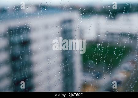 Pluie sur la ville avec gouttes de pluie sur un verre contre certains bâtiments Banque D'Images
