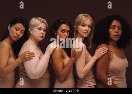 Portrait de groupe d'une jeune femme diversifiée. Cinq femelles de différents types de corps et de courses regardant la caméra en studio. Banque D'Images