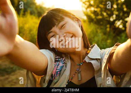 Jeune femme asiatique souriant tout en prenant des photos de selfie à l'extérieur Banque D'Images