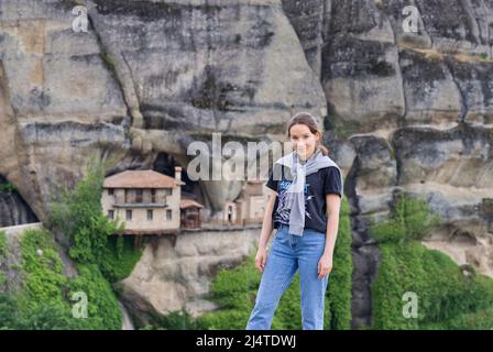 Meteora, Grèce - 29 mai 2021 : une jeune touriste est photographiée sur fond de monastère dans les montagnes. Sommet de la vallée de Meteora. Banque D'Images