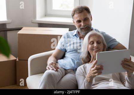 Un couple plus âgé achète des meubles pour la maison en utilisant une tablette sur le déménagement Banque D'Images