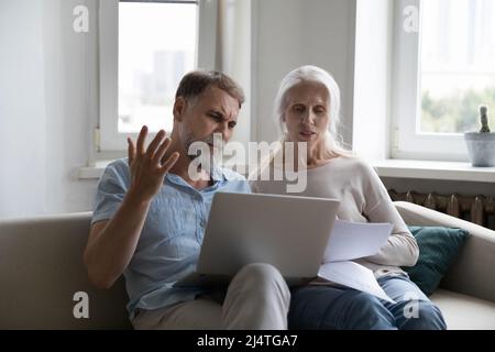 Un couple âgé qui examine les dépenses a l'air agacé en raison de la hausse des services publics Banque D'Images