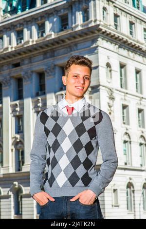 Portrait de l'étudiant de collège. Robe dans un pull à motifs noir, blanc, gris, jeans, mains dans les poches, un jeune homme d'affaires charmant est présent Banque D'Images