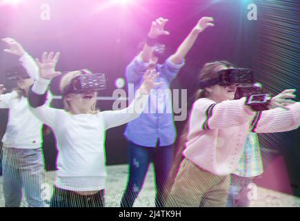Des tweens heureux dans des lunettes VR jouant à des jeux de réalité virtuelle, image tonifiée Banque D'Images