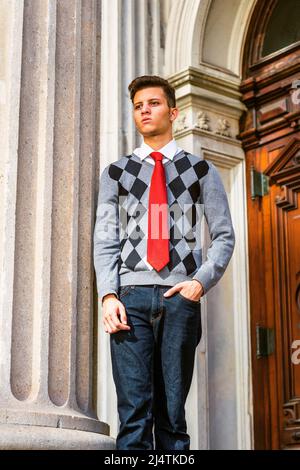 Étudiant de l'American College étudiant à New York. Portant un pull à motifs noir, blanc, gris, cravate rouge, jeans, un jeune homme debout à l'extérieur de vintage Banque D'Images