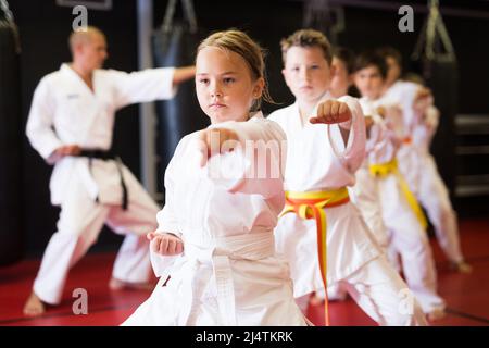 Karaté enfants dans kimono exécutant des mouvements de kata Banque D'Images