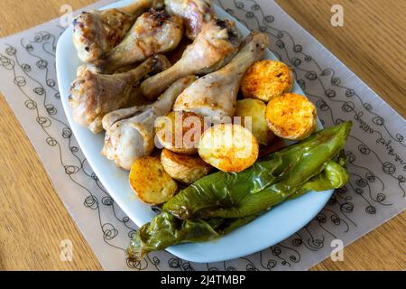 Gros plan d'une grande assiette de cuisses de poulet rôties, de frites et de poivre vert. Banque D'Images