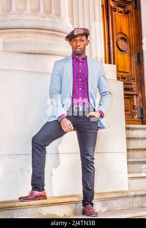 Homme mode urbaine. Porter une casquette Apple Newsboy tendance, une robe de blazer gris clair, un motif rose, noir sous une chemise, un pantalon noir, un cuir marron Banque D'Images