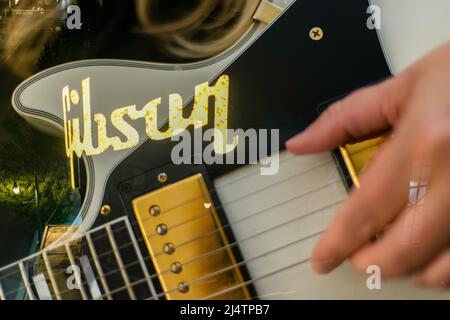 Auteur-compositeur de la chanteuse blonde Femme jouant une guitare Gibson blanche avec exposition multiple avec des lumières de l'usine de guitare Gibson. Banque D'Images