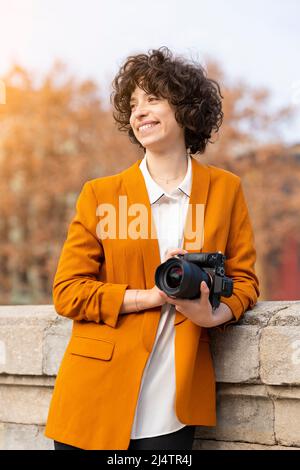 Jeune femme brune aux cheveux bouclés posant avec son appareil photo Banque D'Images