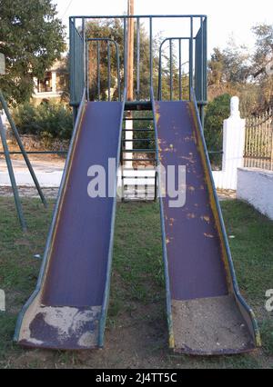 Toboggan pour enfants bien usé dans l'aire de jeux de Xanthates, Corfou, Grèce Banque D'Images