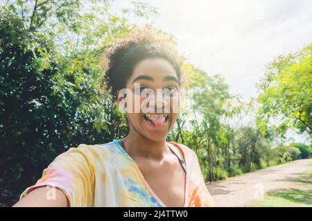 portrait jeune brune femme avec avo pendant la journée dans la campagne souriant et en collant sa langue en regardant l'appareil photo prendre un selfie Banque D'Images