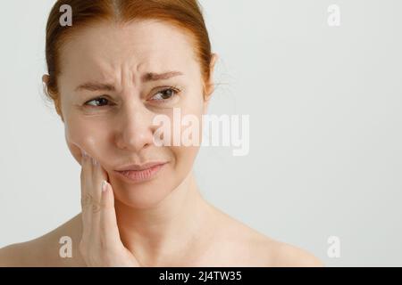 Une femme souffrant de fortes douleurs dentaires, touchant la joue avec la main. Concept de dentisterie. Banque D'Images