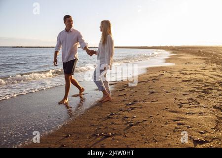 Photo en longueur de couple marchant sur la plage Banque D'Images