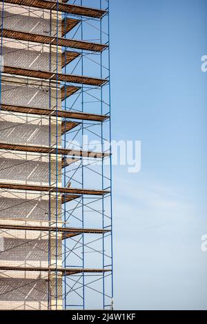 Échafaudage, échafaudage mobile en métal, fond bleu ciel. Un bâtiment moderne est en construction, un échafaudage en métal. Banque D'Images