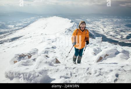Jeune femme grimpant sur la crête enneigée de la montagne Banque D'Images