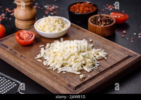 Bloc de fromage mozzarella et morceaux sur planche à découper en bois Banque D'Images