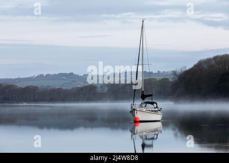 Drake's Pool, Crosshaven, Cork, Irlande. 18th avril 2022. Lors d'un calme lundi de vacances en bord de mer, le bateau à voile Tantine se trouve encore tandis que la brume s'élève de la rivière Owenabue, dans la piscine de Drake, à l'extérieur de Crosshaven, Co. Cork, en Irlande. - Crédit; David Creedon / Alamy Live News Banque D'Images